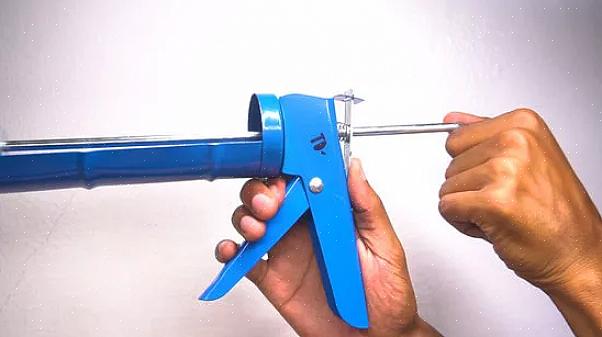 Flytt stangen fremover ved å skyve den frem med spenningens avtrekker til caulk begynner å sive ut fra dysen